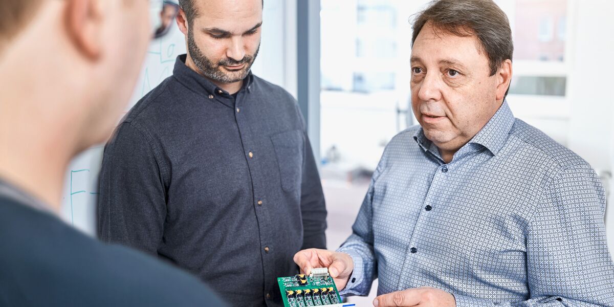 CEO Wolfgang Neu discusses electronic assembly with SMART TESTSOLUTIONS staff.